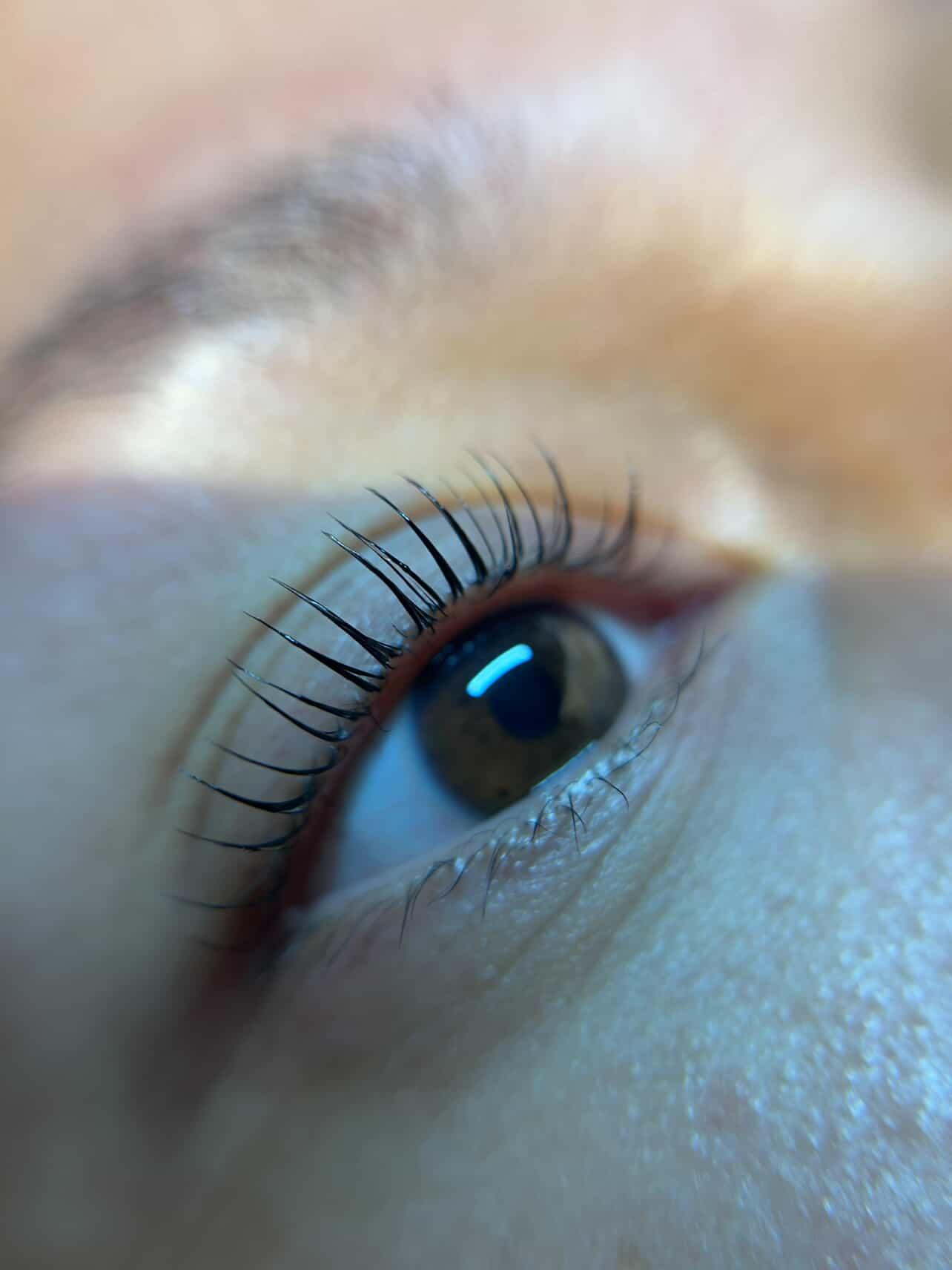 Close-up van een oog met gelifte, gekrulde wimpers na een lash lift